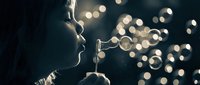 Young woman blowing soap bubbles in dramatic lighting with bokeh background creating magical atmosphere for lifestyle and leisure concepts.