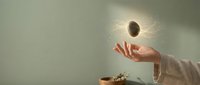 Solar eclipse with corona hovering above open palm against neutral background for astronomy education and cosmic wonder concepts.