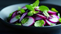 Fresh radish salad with purple onions and mint leaves in white bowl on dark background for healthy eating and vegetarian cuisine recipes.