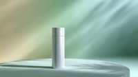 Minimalist silver metallic cylinder container on light surface against blurred mint green background. Clean product photography for cosmetic and packaging design.