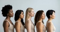 Diverse group of five women in profile view wearing neutral beige tops against white background showcasing multicultural beauty and unity in studio portrait.