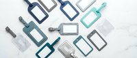 Assorted luggage tags in blue, teal, gray, and clear tones arranged on a white marble surface, showcasing travel accessories for branding mockups.