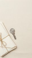 Metallic key placed on neutral beige background next to stacked envelopes tied with twine, representing security, correspondence, and access for design projects.
