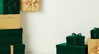 Wrapped gift boxes in emerald green and gold with ribbons arranged on neutral background, ideal for holiday, Christmas, and celebration design projects.