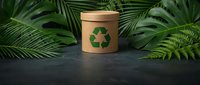 Eco-friendly cardboard container with recycling symbol surrounded by lush tropical palm and fern leaves on dark slate surface for sustainable packaging.