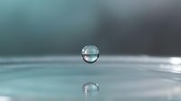 Water droplet floating above calm surface with reflection creating serene minimalist composition for meditation wellness and purity concepts.