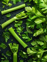 Fresh green celery stalks and parsley leaves scattered on dark background with water drops, top view composition for healthy eating and cooking concepts.