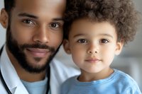 Close up portrait of African American father and young son with curly hair smiling at camera, showing loving family bond and connection in casual home setting.