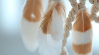 Soft white and beige feathers hanging on natural rope create dreamy boho decoration for interior design and craft projects.