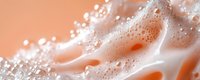 Macro shot of soap foam bubbles in peach and white colors creating abstract texture with soft gradient background. Suitable for cosmetic and skincare advertising.