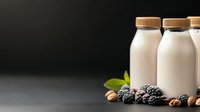 Organic almond milk bottles with fresh blackberries and nuts on dark background for healthy breakfast and vegan lifestyle marketing materials.