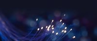 Fiber optic cables with glowing light transmission creating abstract blue technology background for telecommunications and data networks.