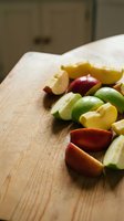Fresh sliced citrus fruits including lime, lemon and orange segments arranged on wooden cutting board in warm kitchen lighting for healthy cooking preparation.