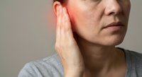Middle-aged Caucasian woman touching ear experiencing pain or hearing problems, healthcare and medical concept for auditory issues or infection.