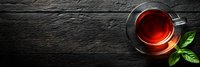 Cup of aromatic black tea with fresh mint leaves on dark rustic wooden background, top view with copy space. Banner format for tea shop menu.