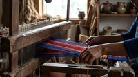 Traditional weaving loom with colorful threads being worked by skilled artisan hands in rustic workshop setting for textile craft and handmade fabric production.