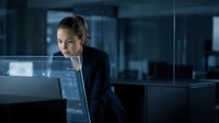 Focused businesswoman in dark blazer examining digital holographic data interface in modern office environment for technology solutions.