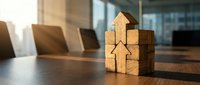 Wooden house blocks arranged on conference table in modern office boardroom representing real estate investment and property development concepts.