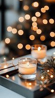 Glowing candles in glass holders with pine branches and soft bokeh lights create cozy winter atmosphere for holiday celebrations and festive decor.