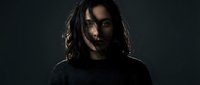 Young woman with long dark hair in dramatic lighting against black background for portrait photography and creative projects.