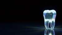 Transparent glass tooth with green core on dark reflective surface for dental healthcare and medical presentations.