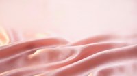 Soft pink silk fabric with elegant folds and gentle lighting creates luxurious textile background for fashion and beauty projects.