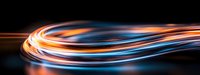 Dynamic light trails with orange and blue glowing streaks flowing in curved motion against dark background, creating futuristic energy effect for technology designs.