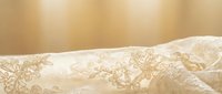 Elegant cream lace fabric with intricate floral patterns draped softly, creating luxurious textile background for wedding, fashion and romantic design projects.