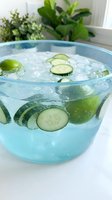 Refreshing cucumber and lime infused water in a clear bowl with ice cubes, perfect for beverage, wellness, and recipe content.