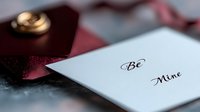 Romantic Valentine's Day card with handwritten Be Mine message next to elegant burgundy gift box with golden bow for love celebration and holiday greeting.