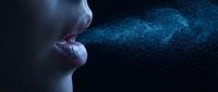 Woman blowing magical blue glittering particles into dark space creating mystical cosmic dust cloud effect for fantasy and spiritual concepts.