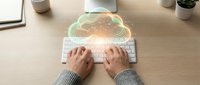 Professional typing on wireless keyboard with glowing cloud computing hologram overlay representing digital transformation and remote work technology.