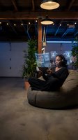 Young African American woman using futuristic holographic tablet interface in modern coworking space with ambient lighting for technology and innovation concepts.