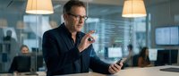 Middle-aged Caucasian businessman in glasses using tablet with holographic display in modern office. Digital technology and innovation concept for presentations.