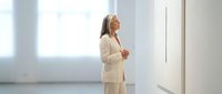 Professional businesswoman in beige suit standing confidently in modern office interior with natural lighting for corporate presentations.