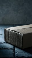 Closed cardboard shipping box on dark stone surface, dramatic moody lighting highlighting texture, for delivery, logistics and e-commerce concepts.