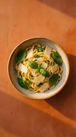 Fresh pasta fettuccine with basil leaves and parmesan cheese served in ceramic bowl on warm terracotta background for culinary content and restaurant menus.
