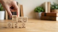 Hand placing wooden cube with sustainability icons including recycling, renewable energy, and environmental symbols on desk for corporate responsibility concepts.