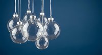 Clear glass Christmas ornaments hanging on silver strings against deep blue background for holiday decorations and festive seasonal designs.