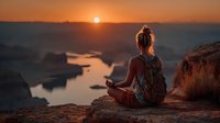 Young woman meditating at sunset on rocky cliff overlooking serene lake, peaceful mindfulness practice in nature, wellness lifestyle concept for relaxation.