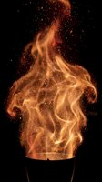 Dramatic fire flames erupting from container with glowing orange and golden sparks against black background, suitable for energy, power, danger, and heat-related design projects.