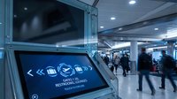 Modern airport terminal with digital directional signage and travelers in motion blur creating dynamic transportation atmosphere.