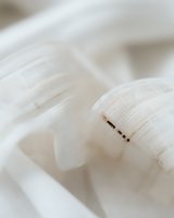 Delicate white feather macro photography showing intricate details and soft texture against light background, creating ethereal minimalist composition.