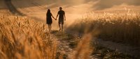 Couple walking hand in hand through golden wheat field at sunset, romantic silhouettes on rural path with warm sunlight creating dreamy atmosphere for love concepts.