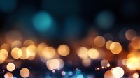 Abstract blurred city lights creating magical bokeh effect in warm orange and cool turquoise tones against dark background, soft dreamy nighttime urban scene.