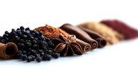 Aromatic spices arranged in colorful row including black peppercorns, star anise, cinnamon sticks and ground seasonings for culinary cooking and food preparation.