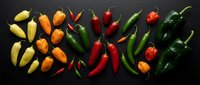Colorful hot chili peppers arranged in groups on dark background. Fresh spicy vegetables for cooking, seasoning and culinary ingredients.