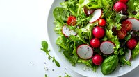 Fresh green salad with sliced radishes and whole cherry radishes on white plate, seasoned with herbs and olive oil, bright healthy food photography.
