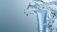 Fresh cosmetic tube with dynamic water splash and droplets against blue background, showcasing skincare product packaging for beauty and personal care advertising.