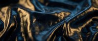 Luxurious golden and blue silk fabric with elegant folds and dramatic lighting creating rich textures for premium fashion and interior design projects.